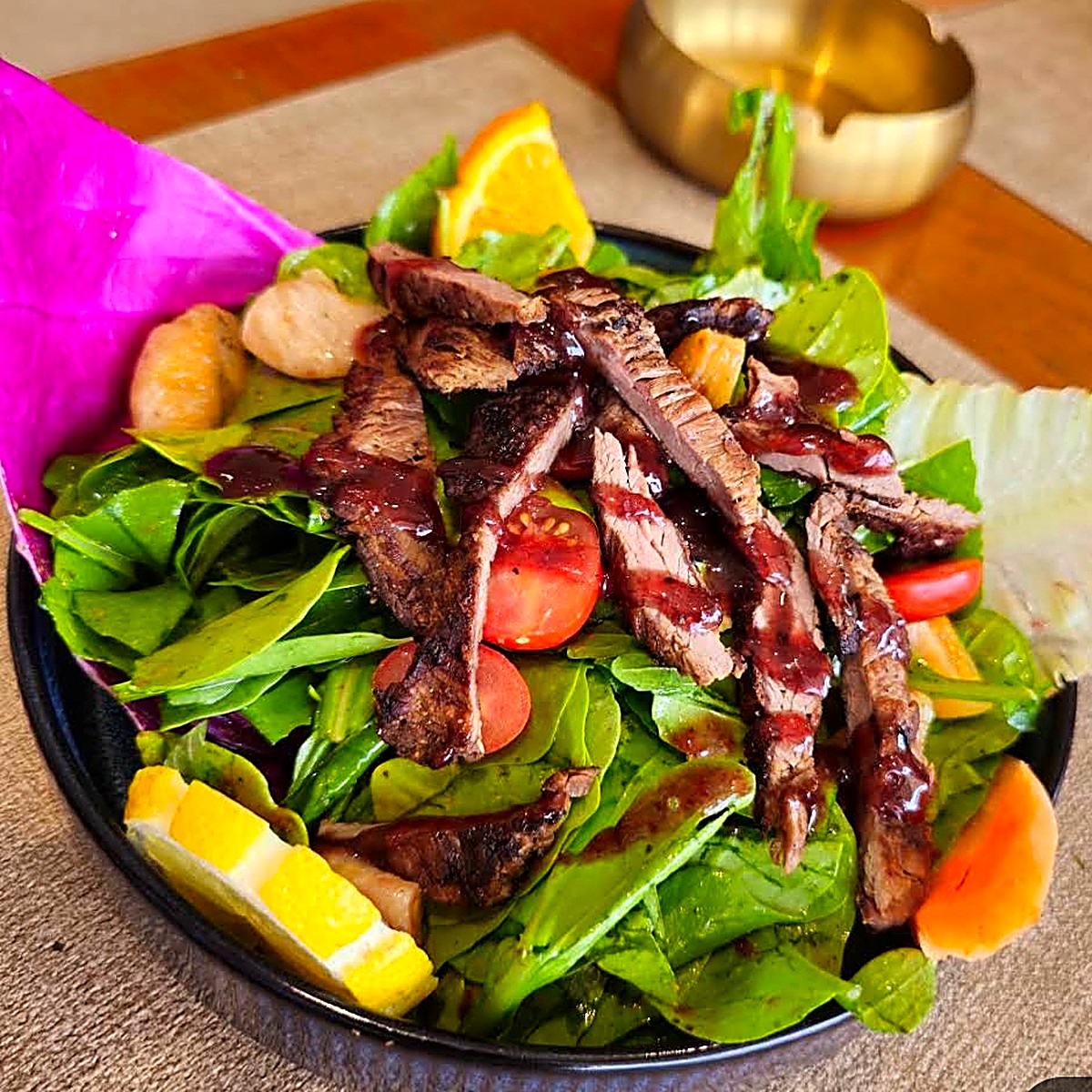Grilled beef slices over fresh greens with pomegranate dressing