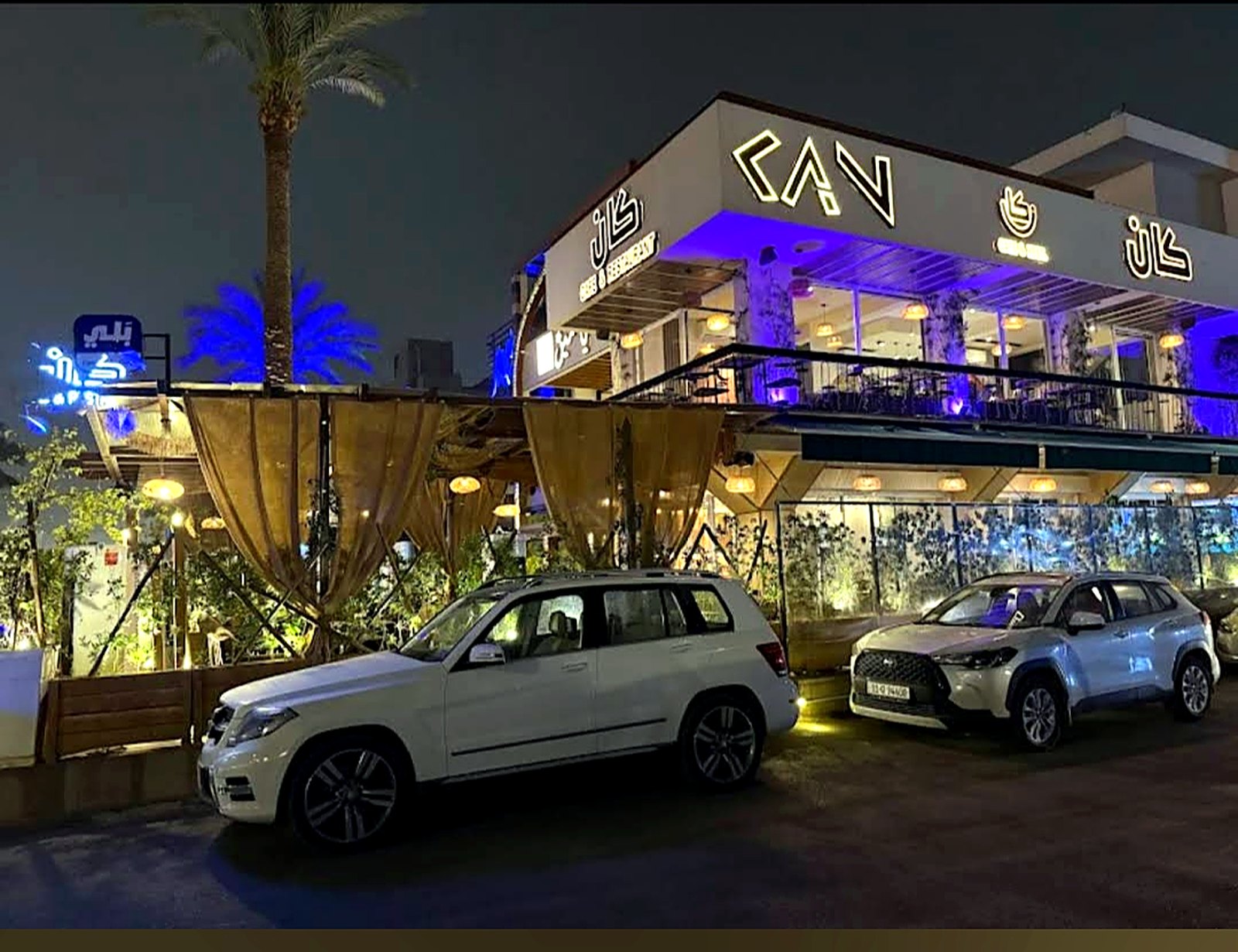 KAN Cafe & Restaurant seen from the street at night, lit sign above the glass front