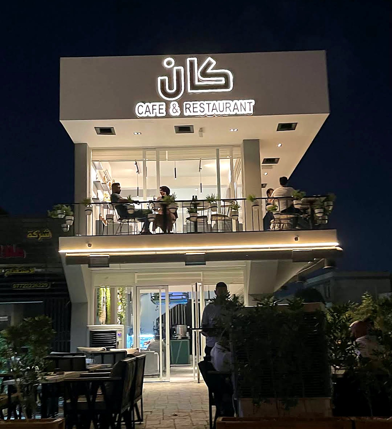 The two-storey KAN facade at night with guests seated on the upper balcony