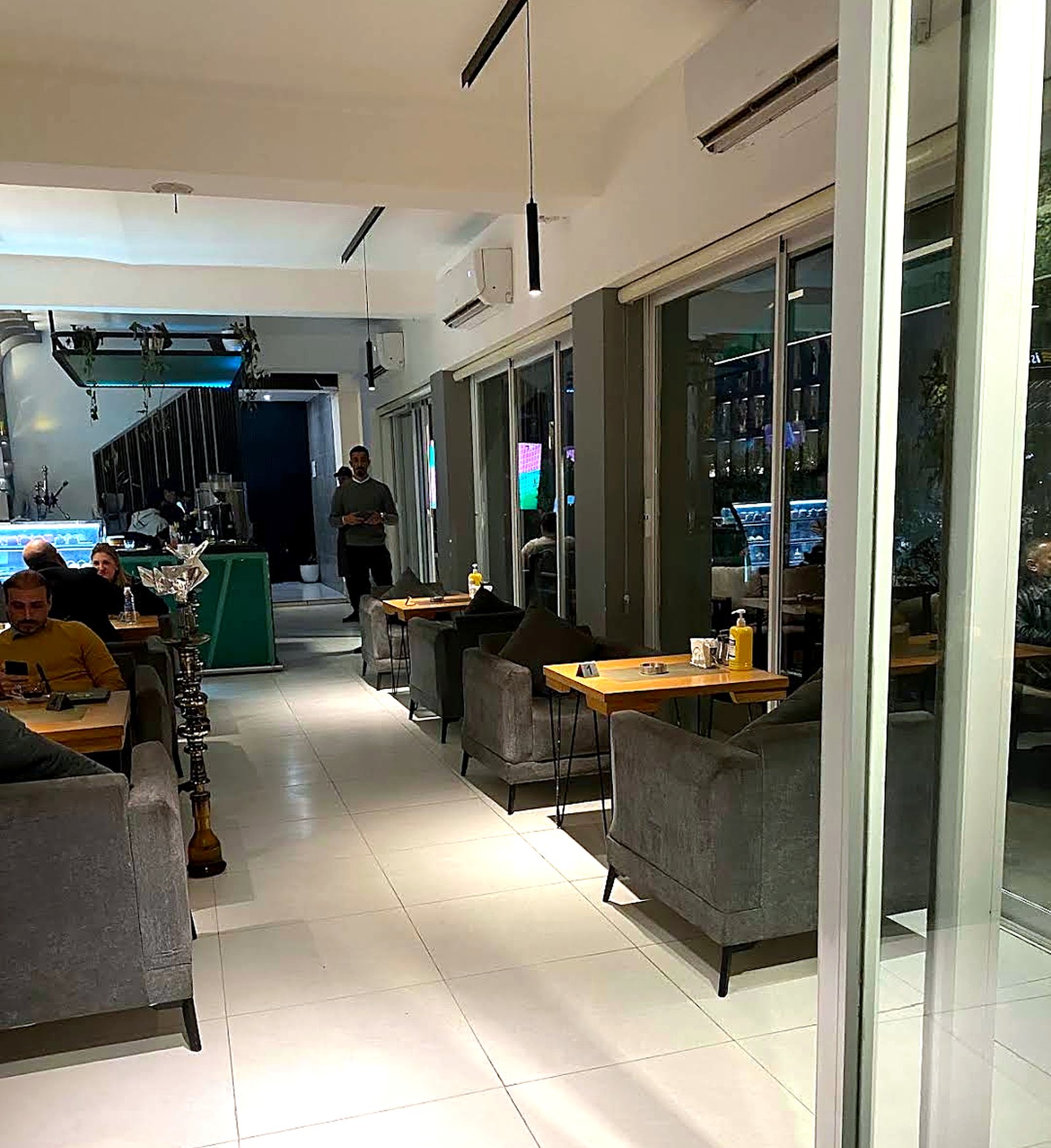 The long dining room at KAN in the evening, wooden tables beside a tall glass front