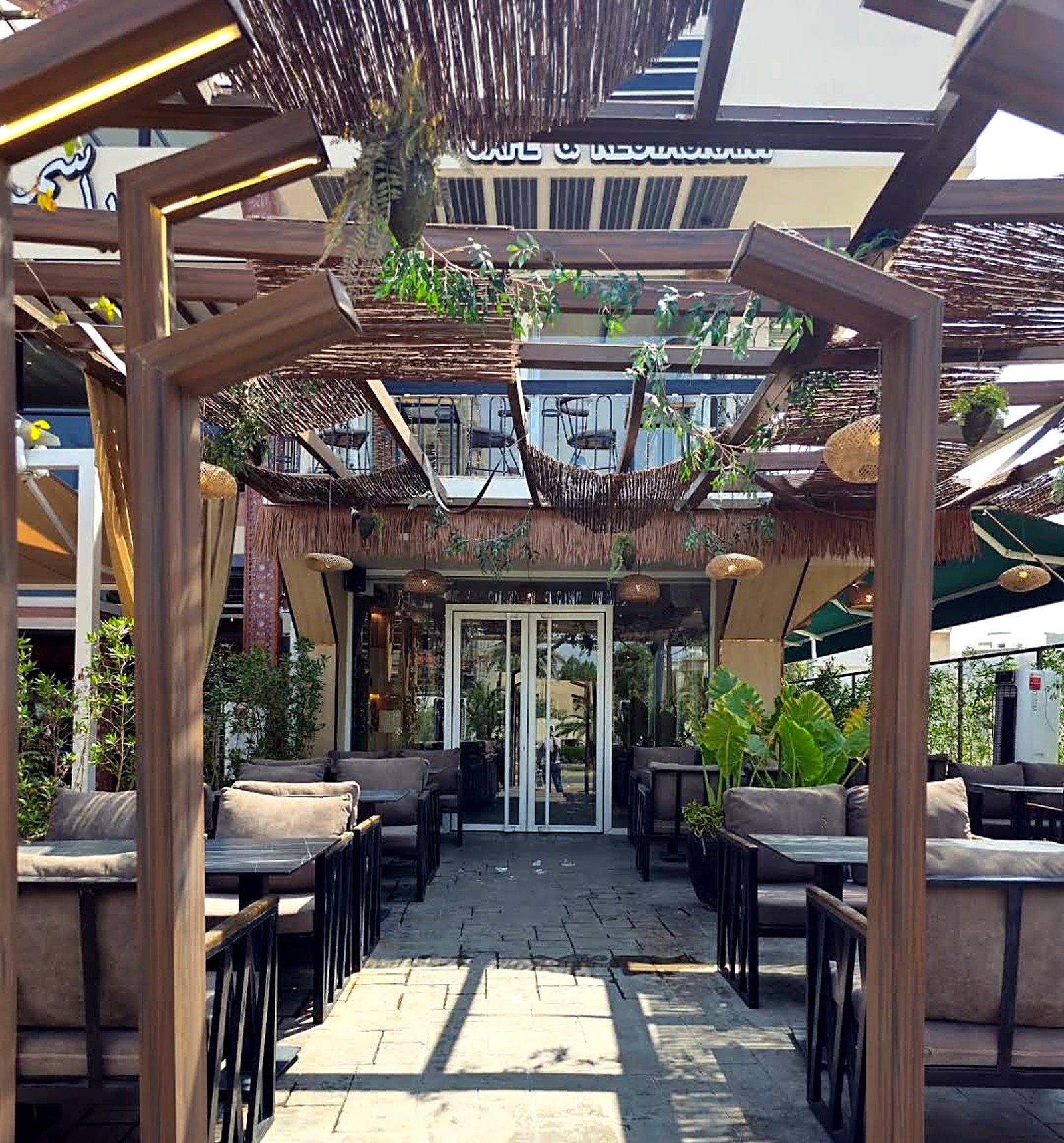 The outdoor terrace at KAN with wooden pergolas, greenery and daylight